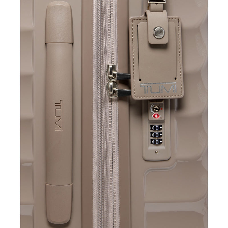 Beige TUMI suitcase with a combination lock on a white background