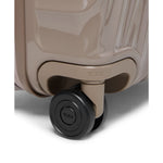 Close-up of a beige TUMI suitcase with a black wheel on a white background