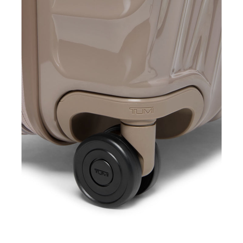 Close-up of a beige TUMI suitcase with a black wheel on a white background