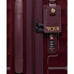 Maroon TUMI suitcase with a luggage tag and handle