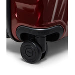 Close-up of a red TUMI suitcase with a black wheel on a white background