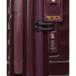 Close-up of a maroon TUMI suitcase with a visible brand logo.