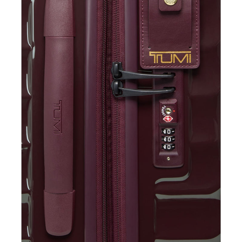 Close-up of a maroon TUMI suitcase with a visible brand logo.