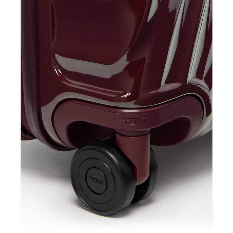 Close-up of a maroon TUMI suitcase with a black wheel on a white background