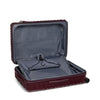 Open burgundy TUMI suitcase with gray interior on a white background