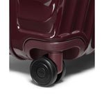 Close-up of a maroon TUMI suitcase with a visible brand logo on a white background