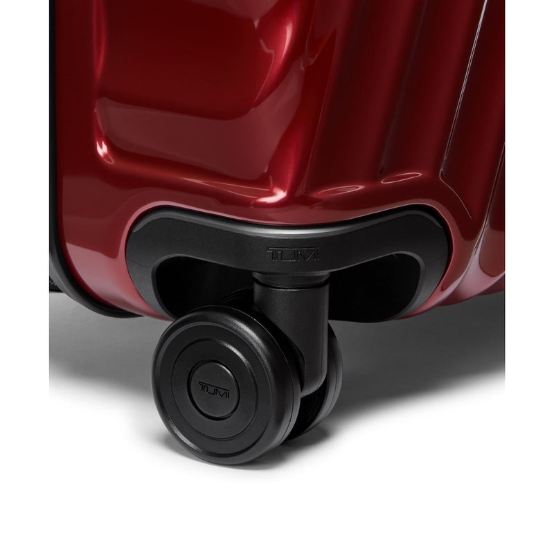 Close-up of a red TUMI suitcase wheel on a white background
