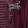 Close-up of a burgundy suitcase with a combination lock, featuring American Tourister branding.