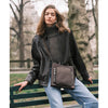 Woman with a Mink TUMI crossbody bag in a park setting