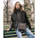 Woman with a Mink TUMI crossbody bag in a park setting