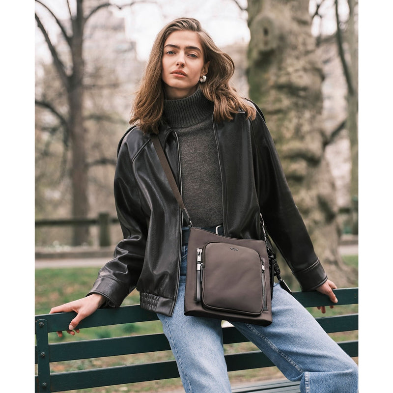 Woman with a Mink TUMI crossbody bag in a park setting