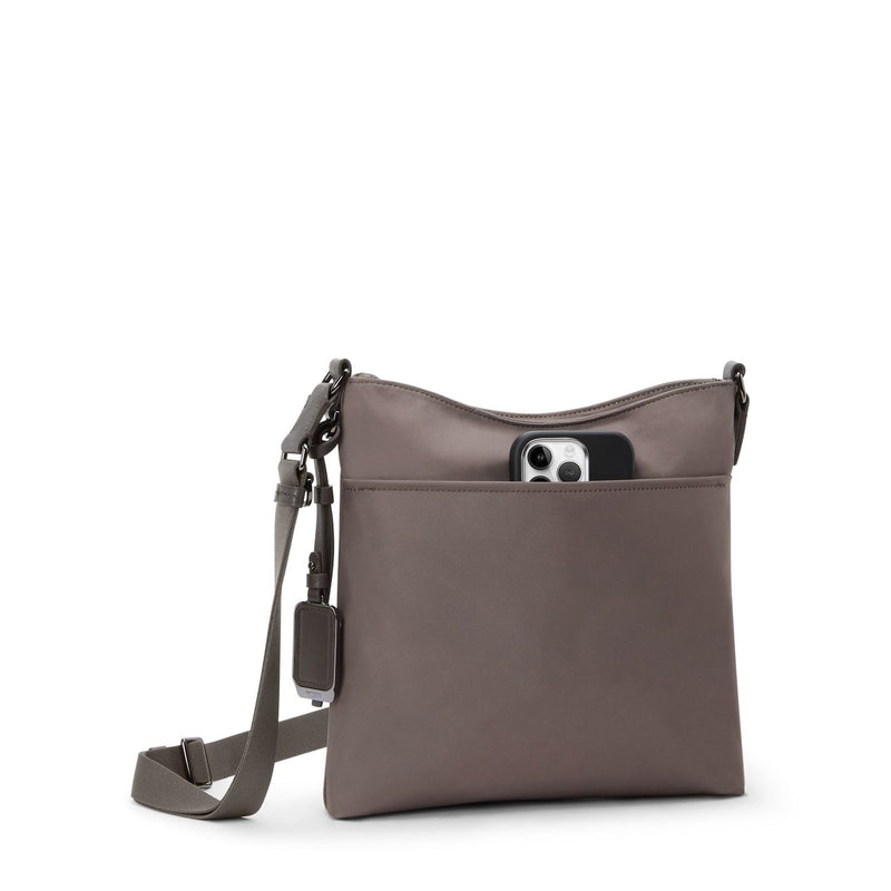 Mink TUMI crossbody bag with a phone in a pocket on a white background
