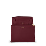 Wine TUMI pouch with gold zipper and logo on a white background