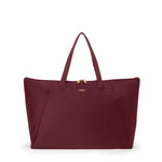 Wine TUMI tote bag with a gold zipper on a white background