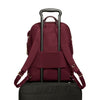 Maroon TUMI backpack with black rolling suitcase on a white background