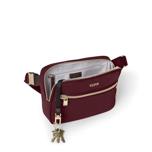 Wine TUMI crossbody bag with gold accents on a white background