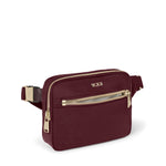Wine TUMI waist bag with gold zippers and accents on a white background