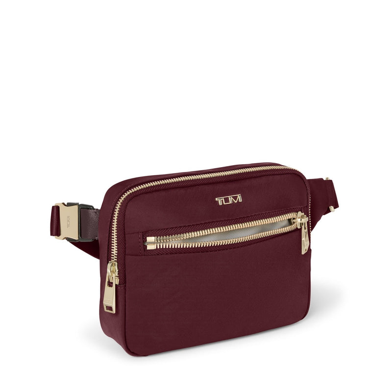 Wine TUMI waist bag with gold zippers and accents on a white background