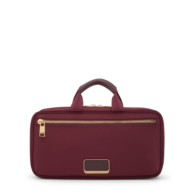 Wine TUMI toiletry bag with gold zipper and accents on a white background