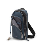 Blue TUMI sling bag with multiple zippers on a white background