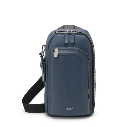 Blue TUMI crossbody bag with a strap on a white background