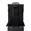 Black TUMI backpack on top of a suitcase with a white background