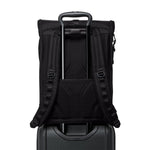 Black TUMI backpack on top of a suitcase with a white background