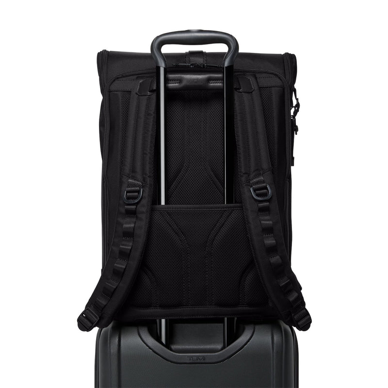 Black TUMI backpack on top of a suitcase with a white background