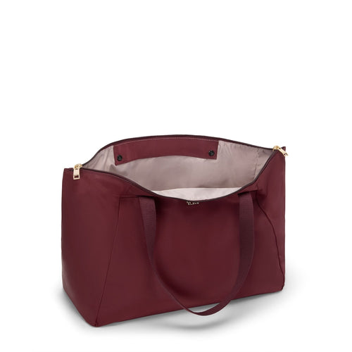 Wine TUMI tote with gold zipper on a white background