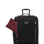 Black TUMI suitcase with gold accents and a matching maroon pouch on a white background