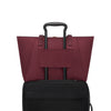 Wine TUMI tote bag on top of a black suitcase on a white background