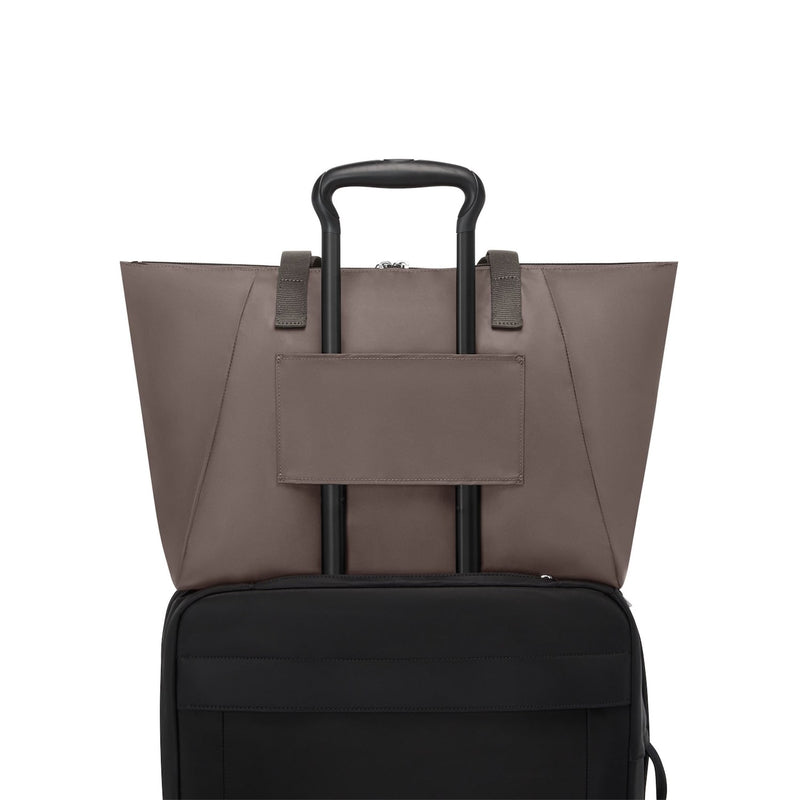 Mink TUMI tote on suitcase with black handle on a white background