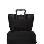 Black TUMI tote bag and black suitcase stacked on a white background