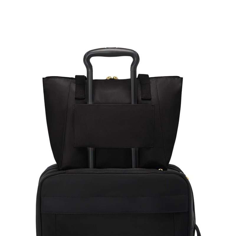 Black TUMI tote bag and black suitcase stacked on a white background