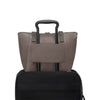 Mink TUMI tote bag on top of a black suitcase on a white background