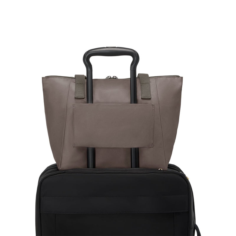 Mink TUMI tote bag on top of a black suitcase on a white background