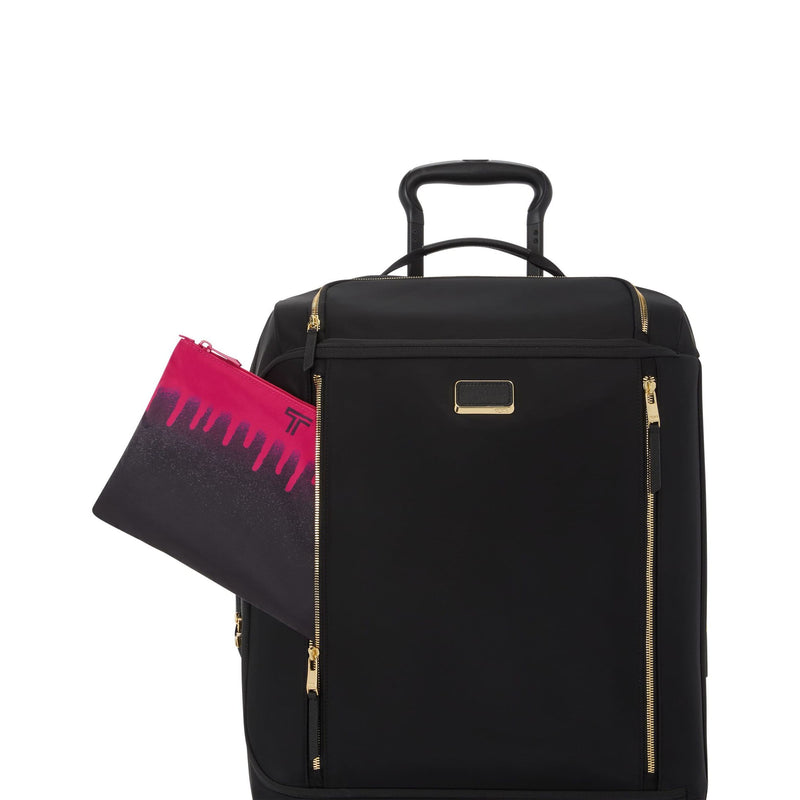 Black TUMI suitcase with gold accents and a pink and black pouch on a white background