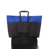 Blue and black TUMI tote bag with a handle on a white background