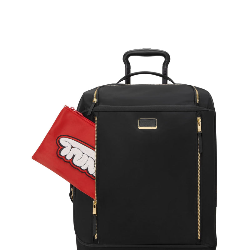 Black TUMI rolling suitcase with gold accents and a red pouch on a white background