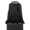 Black TUMI backpack on top of a black suitcase with visible brand logo.