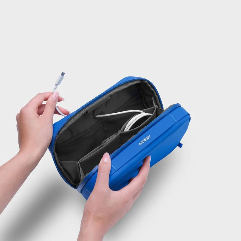 Blue orbitkey travel organizer with a cable being placed inside on a light gray background