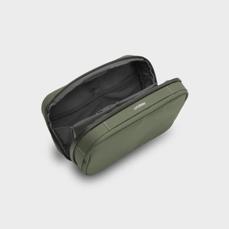 Green orbitkey travel bag with open compartment on a light gray background