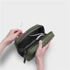 Green orbitkey travel organizer with cables inside, held by hands on a light gray background