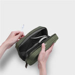 Green orbitkey travel organizer with cables inside, held by hands on a light gray background