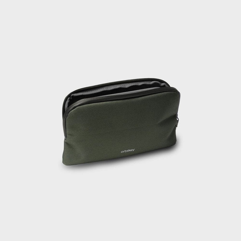 Green orbitkey toiletry bag with a black zipper on a light gray background