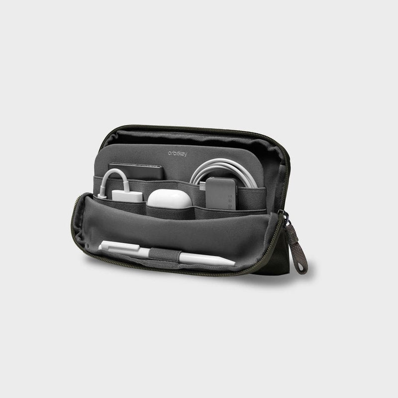Olive orbitkey travel organizer with various items on a light gray background