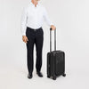 Person in business attire holding a black Victorinox suitcase on a white background