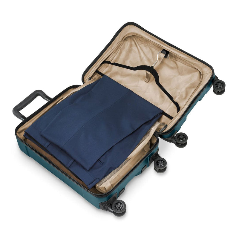 Open Briggs & Riley suitcase with a blue garment inside on a white background