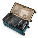 Open ocean Briggs & Riley suitcase with clothes inside on a white background