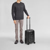 Man holding a black Victorinox suitcase on a light gray background